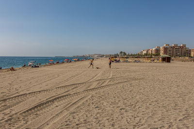 People on beach against clear sky