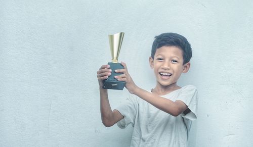 Portrait of smiling boy standing against wall