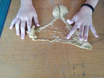 Cropped hand of child playing with clay on table