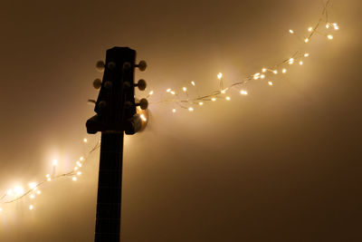 Low angle view of illuminated street lights against sky at night