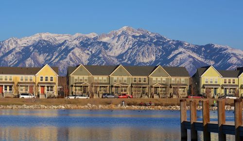 Houses by lake against clear blue sky