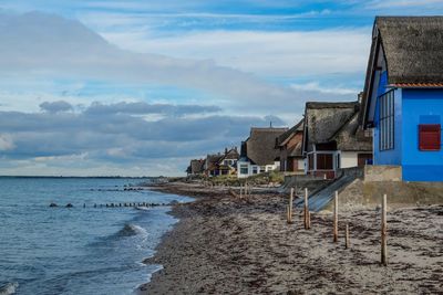 Houses on beach by buildings against sky