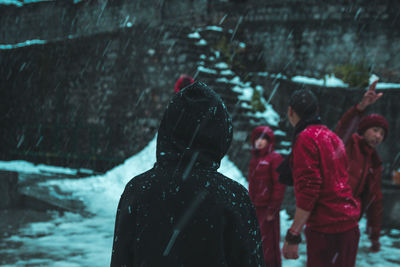 Rear view of people walking on snow covered landscape during rainy season