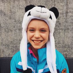 Portrait of smiling boy wearing panda knit hat against wall
