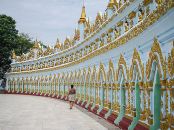 Rear view of woman standing by temple against sky