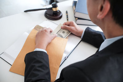 Midsection of businessman holding paper currency in envelop