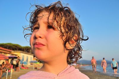 Close-up of girl looking away at beach against clear sky