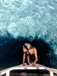 Directly above shot of woman on ladder over sea