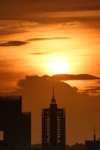 Silhouette of buildings against cloudy sky during sunset