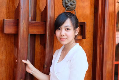 Portrait of young woman standing by door