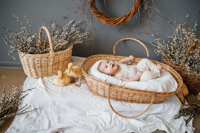 Baby lies in a wicker basket gray background willow eco style