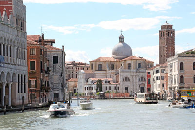 Boats in canal by cathedral against sky in city