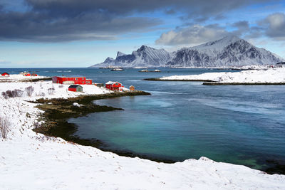 Scenic view of sea by snowcapped mountains against sky