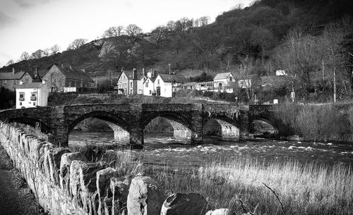 Arch bridge over river amidst buildings