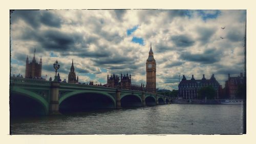 Bridge over river against cloudy sky