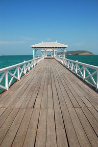 Pier over sea against clear blue sky