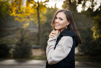 Young woman standing against trees during sunset