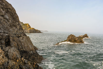 Rock formation in sea against clear sky