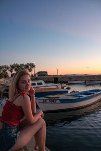 Portrait of young woman in boat against sky during sunset