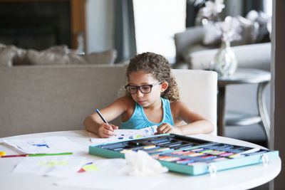 Girl coloring with felt tip pen on paper at table