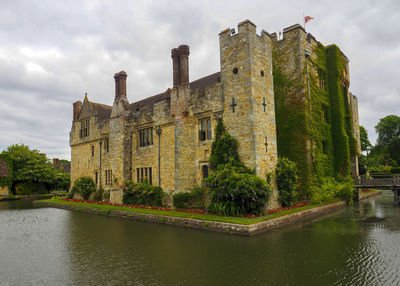 Old building by river against sky