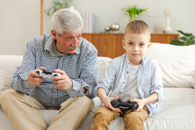 Portrait of boy using mobile phone while sitting on bed at home