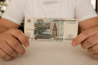 A close-up man holds in his hands an unfolded bill with a face value of 10 rubles. russian money.