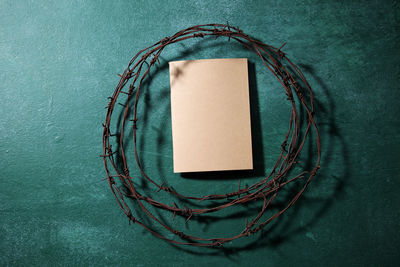 Directly above shot of rusty barbed wire with book on blackboard