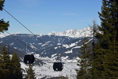 Snowcapped mountains against sky with ski lifts 