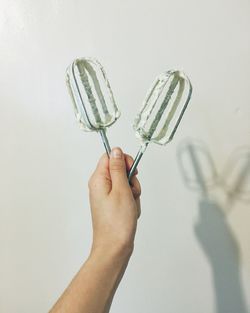 Cropped image of person holding ice candy against white background