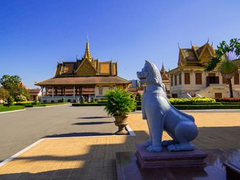 Statue against temple building against clear blue sky