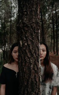 Portrait of a beautiful young woman with tree trunk in forest