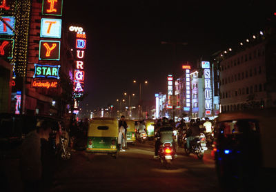 Cars on road by illuminated buildings in city at night