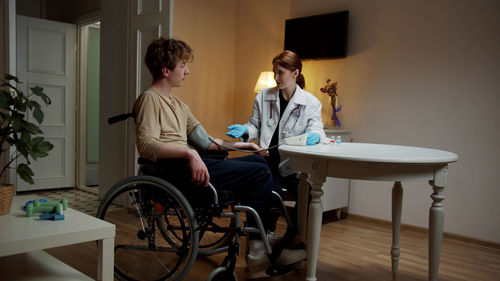 Doctor talking with patient sitting on wheelchair