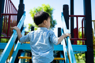 Boy playing on railing against clear blue sky