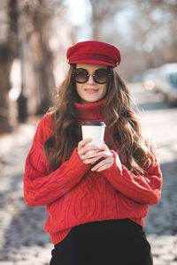 Portrait of pregnant woman holding coffee cup standing at park