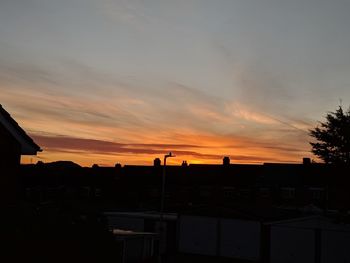 Silhouette buildings against sky at sunset