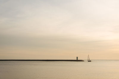 Sailboat sailing on sea against sky during sunset