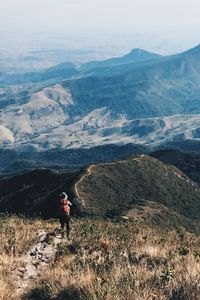 Rear view of hiker standing on mountain against sky