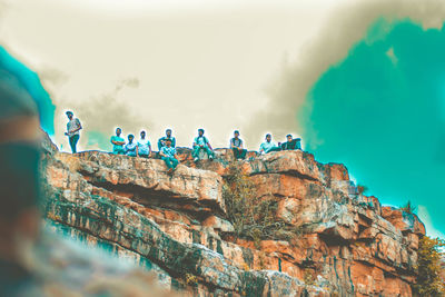 People on rock formation against sky