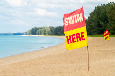 Information sign on beach against sky