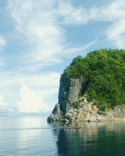 Scenic view of cliff near sea against cloudy sky