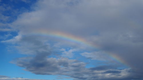 Low angle view of rainbow against blue sky