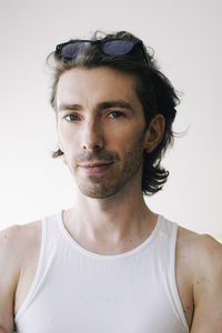 Portrait of man in undershirt against white wall