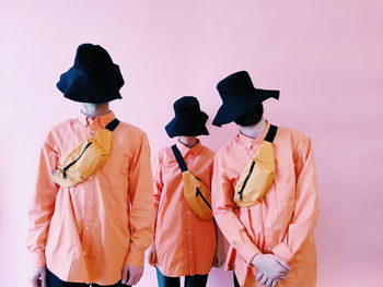 Rear view of people standing against pink background