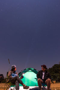 People sitting against blue sky at night