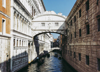 Canal amidst buildings against blue sky in city during sunny day