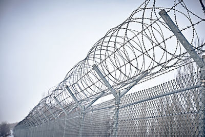 Low angle view of barbed wire fence against sky