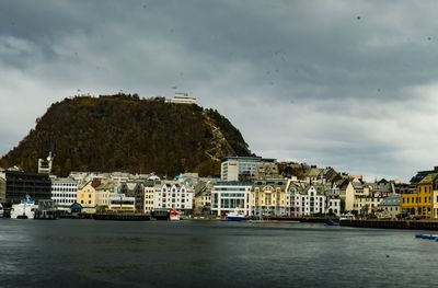 Buildings by river against sky in city