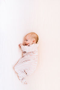 View from above of a newborn baby girl in striped pajamas